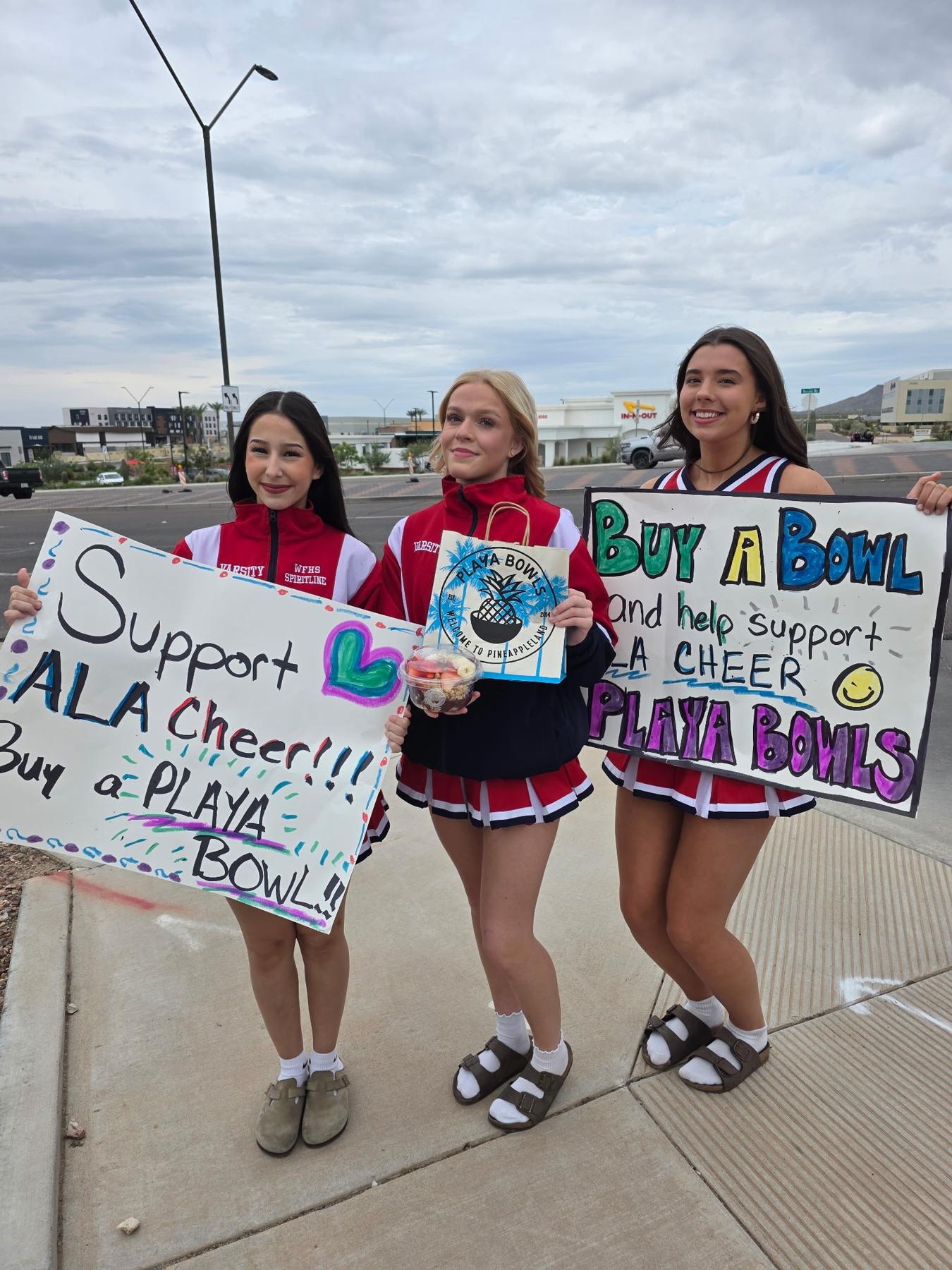 Cheerleaders out front with Buy a Bowl signs